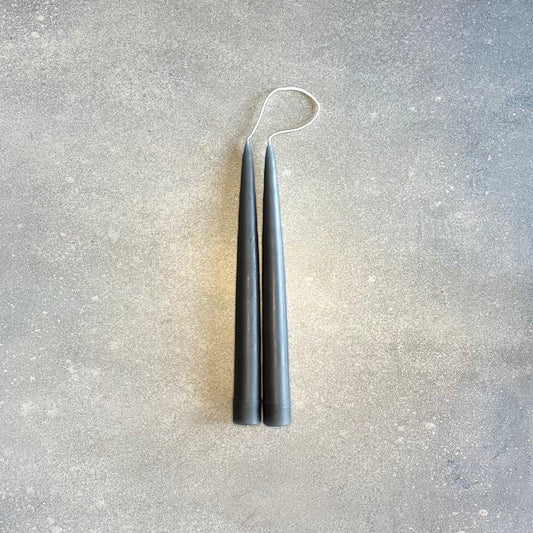 A pair of DANICA DESIGNS HAND-DIPPED TAPER CANDLES hanging on a Gestalt Haus wall.